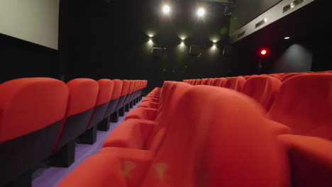 Sideway-view-of-red-cinema-armchairs-in-an-empty-movie-theatre-.-Smooth-shot